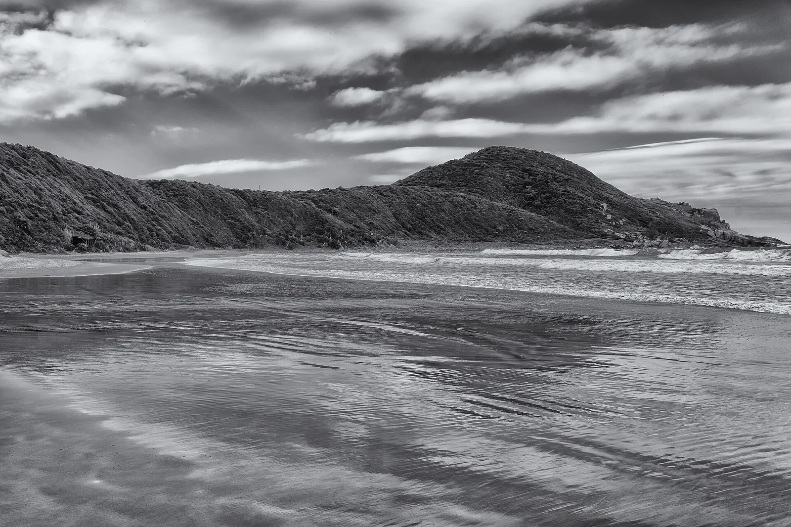 Praia do Rosa em preto e branco, com a faixa de areia, o mar e os morros que fecham a enseada